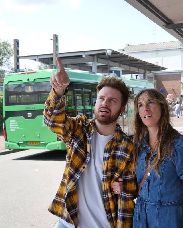 Een vrouwelijke en mannelijke reiziger kijken naar vertrektijden op het station