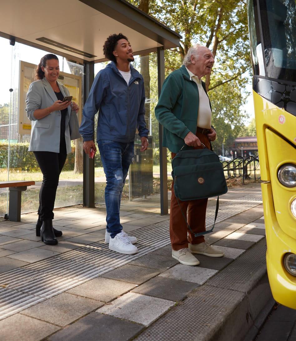Drie reizigers staan in de rij voor de bus