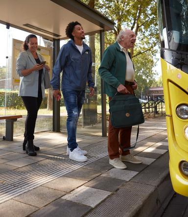 Drie reizigers staan in de rij voor de bus