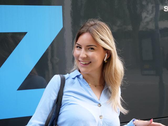 Vrouwelijke reiziger met grote glimlach staat voor een bus